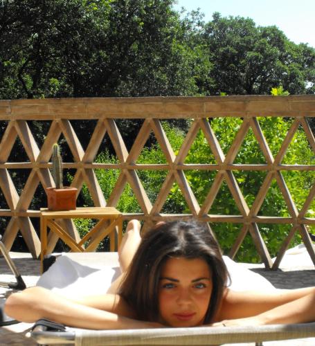 a woman laying on a bed in front of a fence at B&B and Wellness Il Pomario di Montepiglio Resort Naturista in Amelia