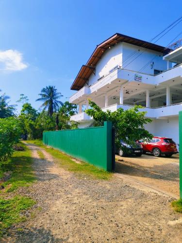 a building with a green fence next to a parking lot at Sea Wind Villa Thalpe in Talpe