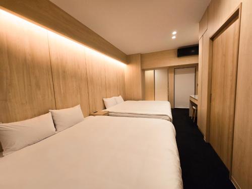 a hotel room with two beds and a desk at UH Suite Namba Station in Osaka