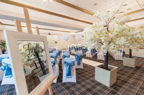 a room with chairs and a tree in the middle at Airport Inn & Spa Manchester in Wilmslow