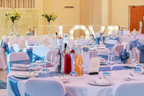 a room with white tables and chairs with wine glasses at Airport Inn & Spa Manchester in Wilmslow