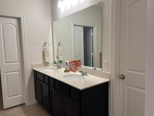 a bathroom with two sinks and a large mirror at Balmoral LakeSide 5br 4ba House in Humble