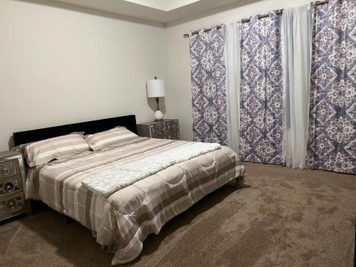a bedroom with a bed and two windows with curtains at Balmoral LakeSide 5br 4ba House in Humble