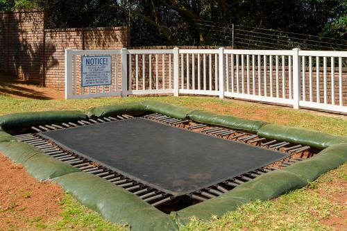 an empty trampoline in a yard with a fence at Illovo Beach Club in Amanzimtoti