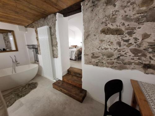a bathroom with a white tub and a stone wall at La SUITE delle Scuderie, con Vasca da bagno in stanza, PetFiendly con Area Cani in Baselga di Pinè