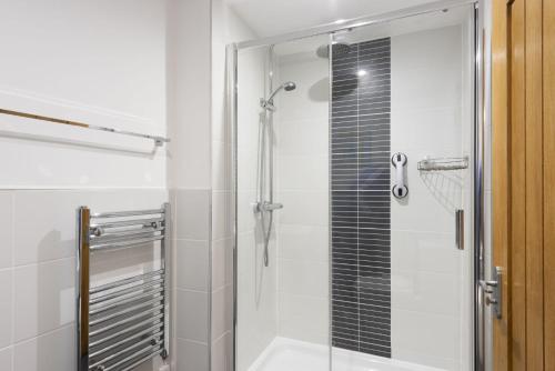 a bathroom with a shower with a glass door at Samson Cottage in Saint Mawgan