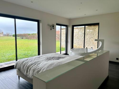 - une chambre avec un grand lit, une baignoire et des fenêtres dans l'établissement Villa De L'Amiral - LUXE ET DETENTE A POMMEVIC, à Pommevic