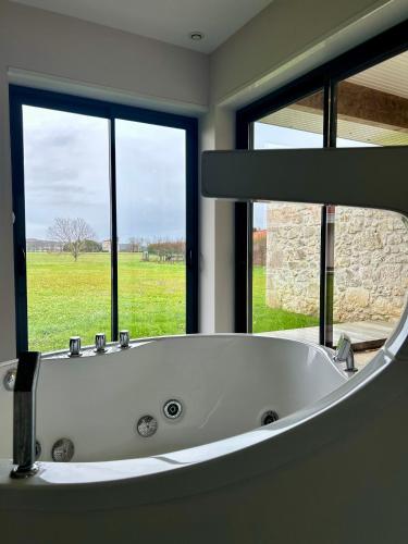 une baignoire dans une salle de bain avec une grande fenêtre dans l'établissement Villa De L'Amiral - LUXE ET DETENTE A POMMEVIC, à Pommevic