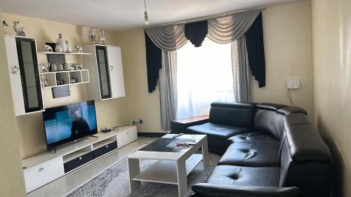 un salon avec un canapé en cuir noir et une télévision dans l'établissement Thalia Appartement, à Nairobi