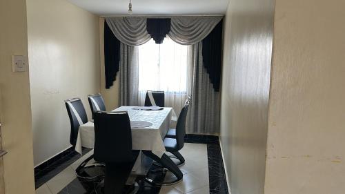 une salle à manger avec une table et des chaises et une fenêtre dans l'établissement Thalia Appartement, à Nairobi