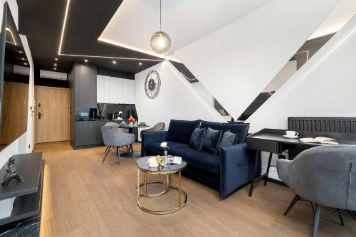 a living room with a blue couch and a table at Luksusowe, Klimatyzowane Studio w Centrum Katowic z Pięknym Widokiem na Miasto, Wanną z Hydromasażem, Biurkiem i Parkingiem by Renters Prestige in Katowice