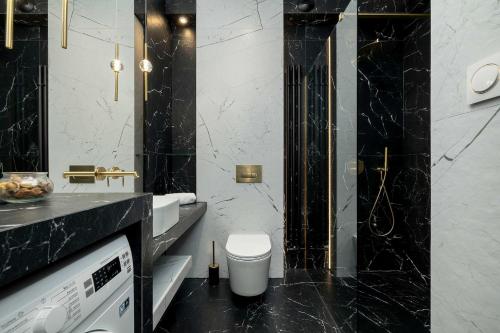 a black and white bathroom with a toilet and a sink at Luksusowe, Klimatyzowane Studio w Centrum Katowic z Pięknym Widokiem na Miasto, Wanną z Hydromasażem, Biurkiem i Parkingiem by Renters Prestige in Katowice