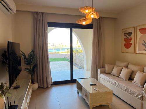 a living room with a couch and a large glass door at Stylish 1BR Ground With Free Pool & Lagoon Access In Gouna in Hurghada