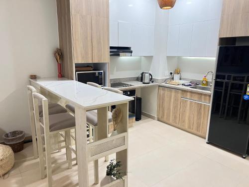 a kitchen with a white table and a black refrigerator at Stylish 1BR Ground With Free Pool & Lagoon Access In Gouna in Hurghada