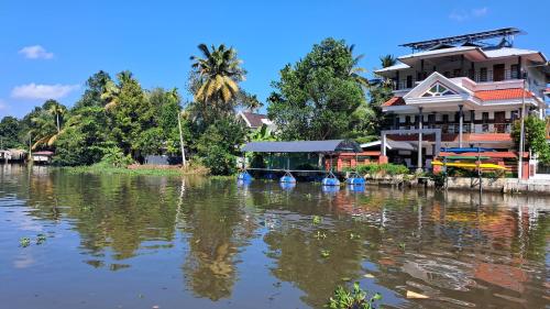 a river with a house and a boat in the water at Mango Kerala Homes in Kumarakom