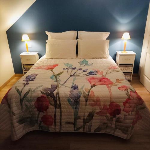 - une chambre avec un lit doté d'une couverture florale dans l'établissement Jolie Maison de Campagne en pierre de tuffeau, à Longué