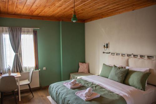 a green bedroom with a large bed and a table at Oreades Guesthouse in Koukouli