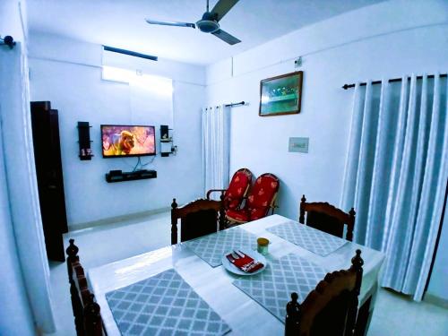 a dining room with a table and chairs and a television at Alappuzha Family Vacation Villa - LAYANILA in Alleppey