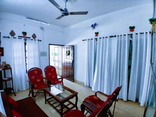 a living room with red chairs and a table at Alappuzha Family Vacation Villa - LAYANILA in Alleppey