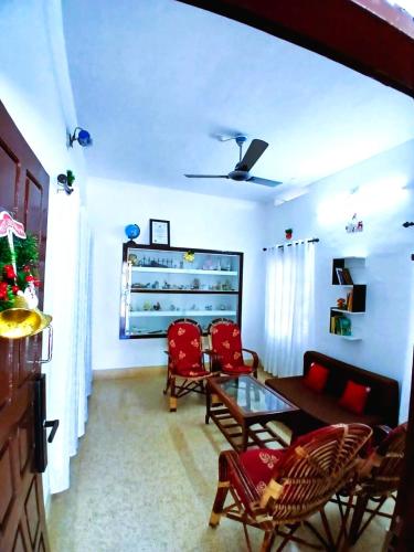 a living room with a table and red chairs at Alappuzha Family Vacation Villa - LAYANILA in Alleppey