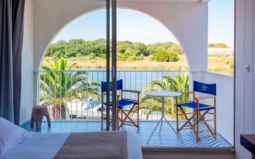 a room with a bed and a balcony with a table and chairs at Les Bulles de Mer - Hotel & Spa sur la Plage in Saint-Cyprien