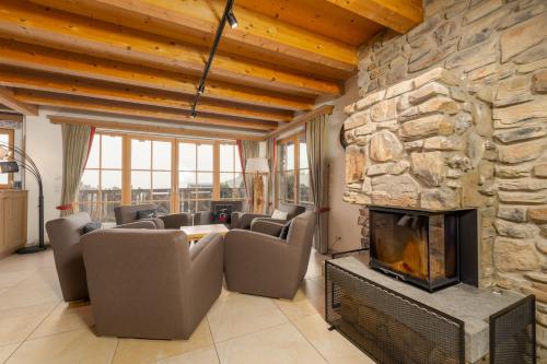 a living room with a fireplace and a stone wall at AvenidA Panorama Chalet by Alpin Rentals in Piesendorf