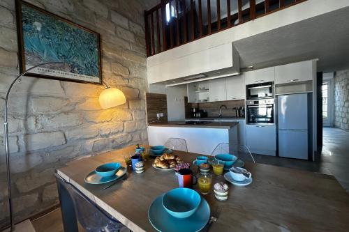 una cucina con tavolo in legno e piatti blu di Maisonnette de Plage sur les Toits Appart 1 chambre 1 mezzanine avec Vue a Le Grau-du-Roi