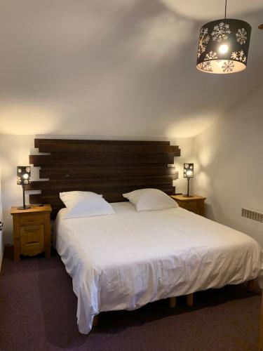 - une chambre avec un grand lit blanc et un lustre dans l'établissement Les fermes de saint gervais, à Saint-Gervais-les-Bains