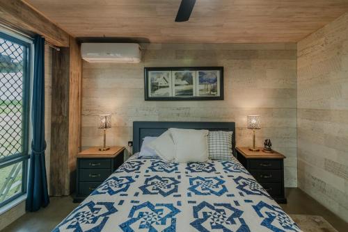 Bridge Moore Lodge في Bucca: غرفة نوم مع سرير مع موقف ليلتين ونوافذ