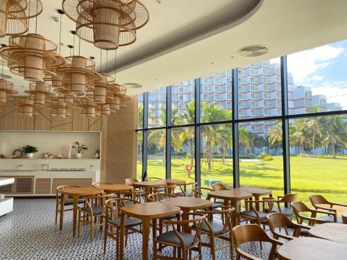 a restaurant with tables and chairs and large windows at Horizon Hub - Cam Ranh Resort Apartment in Cam Ranh International Airport
