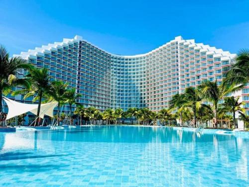 a resort with a large swimming pool and palm trees at Horizon Hub - Cam Ranh Resort Apartment in Cam Ranh International Airport