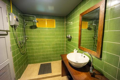 a green bathroom with a sink and a mirror at 11 Rooms in Chiang Dao