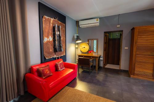 a living room with a red chair and a desk at 11 Rooms in Chiang Dao