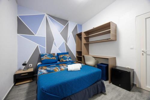 a bedroom with a blue bed with a geometric wall at Villa Les Pierres Précieuses in Rémiré