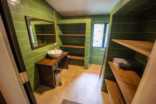 a green bathroom with a sink and a mirror at 11 Rooms in Chiang Dao