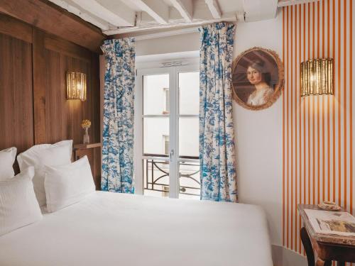 a bedroom with a bed and a mirror and a window at Hotel Madeleine De Senlis in Paris
