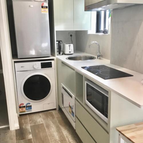 a kitchen with a washing machine and a sink at Modern studio, Minutes to Ferry, City, CBD in Sydney