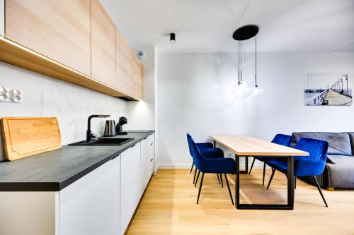 a kitchen and dining room with a table and blue chairs at ReVital Mechelinki by Homeprime Parking Free in Mechelinki