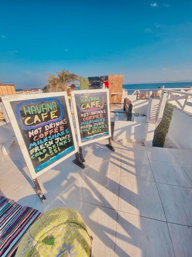 two signs on the beach with the ocean in the background at Havana House in Dahab