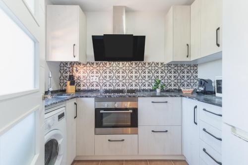 a kitchen with white cabinets and a stove top oven at Urbanización Jardín del Golf 1 in Novo Sancti Petri