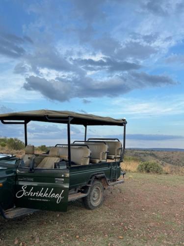 a green vehicle parked in the middle of a field at Schrikkloof Private Nature Reserve, home of The Lions Foundation in Bela-Bela