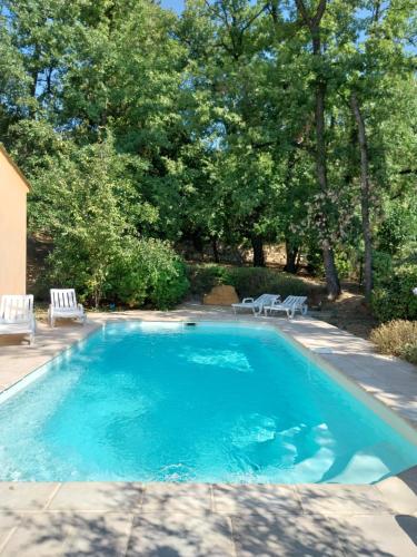- une piscine avec 2 chaises blanches et des arbres dans l'établissement Très belle villa 2 avec piscine, à Callian