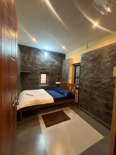 a bedroom with a bed and a stone wall at Elora Resort Wayanad in Kalpetta