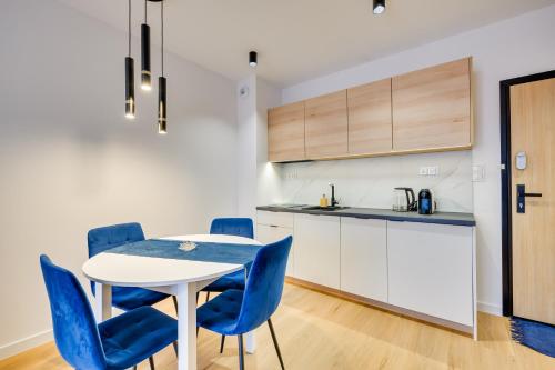 a kitchen and dining room with a table and blue chairs at ReVital Mechelinki by Homeprime Parking Free in Mechelinki