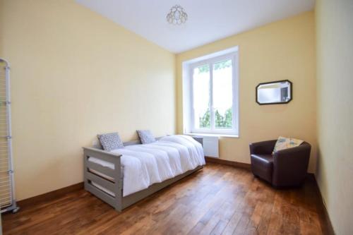 une chambre avec un lit, une fenêtre et une chaise dans l'établissement Appartement 4 pers à 300m de la gare SNCF, à Dinan