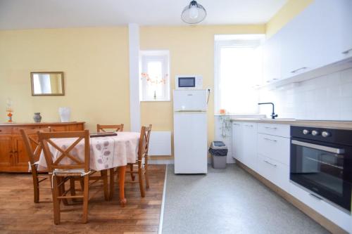 une cuisine avec une table et un réfrigérateur blanc dans l'établissement Appartement 4 pers à 300m de la gare SNCF, à Dinan