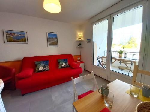 un salon avec un canapé rouge et une table dans l'établissement Saint Palais sur Mer - STUDIO - résidence LES SABLES D'OR - CENTRE VILLE, à Saint-Palais-sur-Mer
