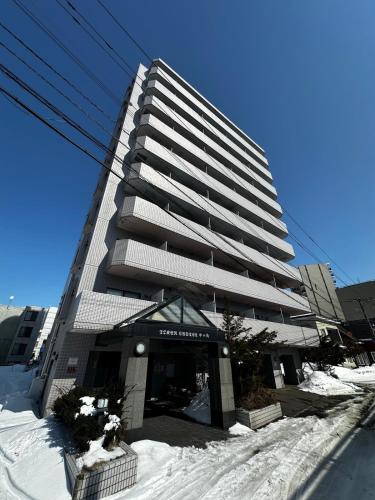 a tall building with snow in front of it at 8-1閑静なエリア豊平川目の前でゆったりと静かな旅行可能 in Sapporo