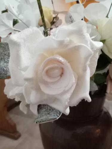 a white rose in a vase with white flowers at Appartamento Caterina in Cairo Montenotte