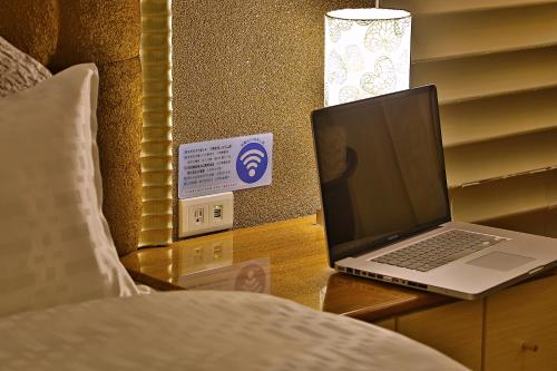 a laptop computer sitting on a desk next to a bed at 薇風情汽車旅館 - 台南館 in Liujia